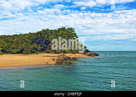 Palm Cove Beach nell'estremo Nord all'inizio dell'estate - all'estremità settentrionale, al largo del molo - la vista sull'acqua fino agli affioramenti rocciosi e promontorio Foto Stock