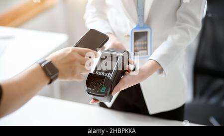 Immagine ravvicinata di un uomo che paga le sue fatture tramite smartphone con terminale di pagamento. Servizio portafoglio digitale, Mobile banking, scansione codice QR. Foto Stock