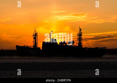 Silhouette di un rompighiaccio sullo sfondo del tramonto. Vapore dall'acqua durante il gelo intenso Foto Stock