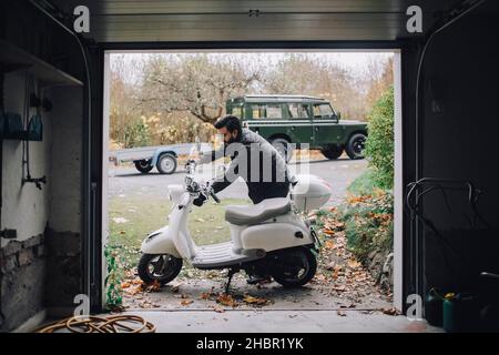 Uomo medio adulto che ripara il motore elettrico in garage Foto Stock