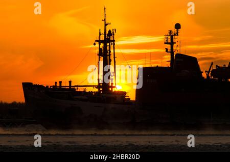 Silhouette di un rompighiaccio sullo sfondo del tramonto. Vapore dall'acqua durante il gelo intenso Foto Stock