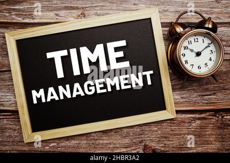 Time Management testo su lavagna e sveglia su sfondo di legno Foto Stock