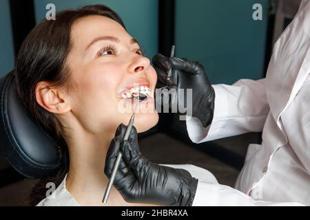 Una giovane donna in una clinica dentale con un dentista. La donna con le bretelle sorride. Il concetto di denti sani. Foto Stock