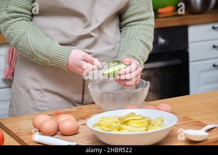 Giovane donna irriconoscibile che cucinava una ricetta con avocado, uova e patate. Foto Stock