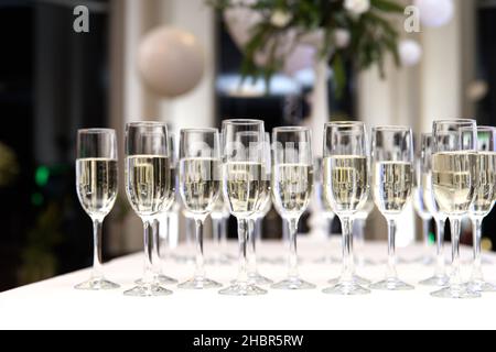 Un sacco di bicchieri da vino con uno champagne o vino bianco. molto bicchieri con champagne durante la festa. fuoco selettivo Foto Stock