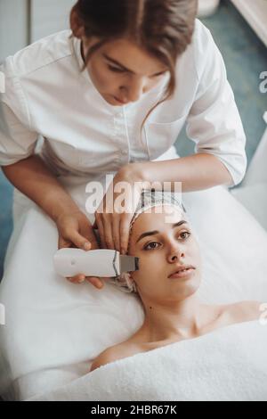 Primo piano ritratto di una donna che riceve ultrasuoni cavitazione viso peeling. Salone di bellezza. Cosmetologia procedura di bellezza. Foto Stock