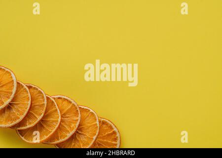 una vista ad angolo alto di una fetta di frutta secca di arancio su sfondo giallo Foto Stock