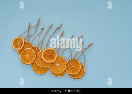 una vista ad angolo alto di una fettina di frutta secca di arancia con un filo su sfondo blu chiaro Foto Stock