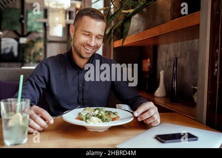 Un uomo d'affari sorridente sta pranzando al ristorante Foto Stock