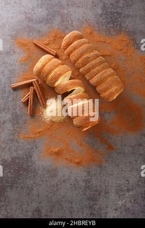 Trdelnik è una dolce tradizionale a base di pasta di lievito tenuta intorno a un bastone, poi fritto e cosparso di zucchero e cannella in primo piano sul tavolo Foto Stock