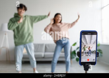 Video di registrazione della coppia asiatica millennial, divertimento, danza con la fotocamera del telefono cellulare a casa, fuoco selettivo Foto Stock