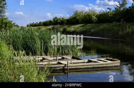 Un bel fiume con due vecchie barche da pesca fluviali legate sulla riva Foto Stock