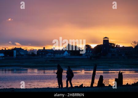 La gente si è vista sulla spiaggia al tramonto con Langstone Harbor e Mill Hampshire Inghilterra sullo sfondo Foto Stock