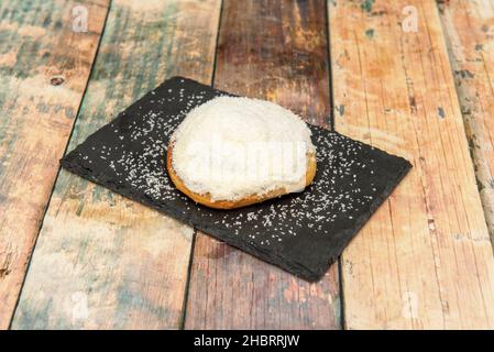 rotolo di cannella con guarnizione grattugiata di cocco su piastra nera di ardesia Foto Stock