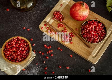 Ancora vita con grani di melograno di frutta rossa su piatti e cucchiai Foto Stock