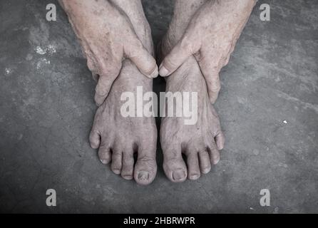 Mani e piedi dell'anziano asiatico. Concetto di salute e cura delle articolazioni, e l'invecchiamento della pelle. Isolato su sfondo concreto. Foto Stock