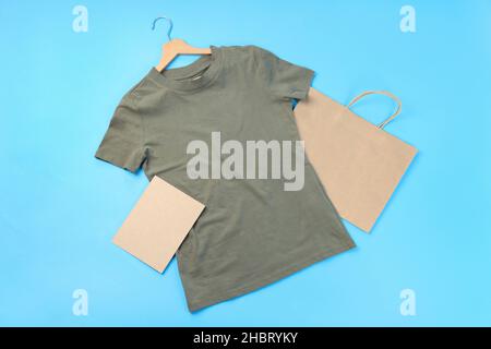 T-shirt, sacchetto e foglio di cartone vuoti su sfondo blu Foto Stock