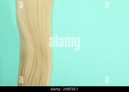 Una ciocca di capelli biondi su sfondo menta Foto Stock
