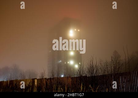 Edificio residenziale a più piani in nebbia fitta la sera Foto Stock