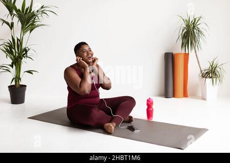 Donna nera in sovrappeso estatica che ascolta musica durante l'allenamento Foto Stock