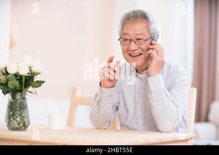 Uomo anziano che utilizza uno smartphone per effettuare chiamate a casa Foto Stock