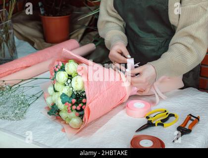 Fiorista femminile che crea bouquet bello sul posto di lavoro in negozio di fiori, primo piano. Laboratorio di Floristica. Facendo i bouquet bei del fiore e le decorazioni floreali Foto Stock