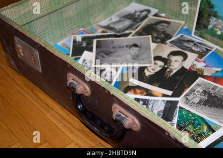 Apri la vecchia valigia sul pavimento piena di ricordi fotografici. Foto in bianco e nero Foto Stock