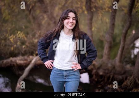 Adolescente donna in piedi circondato da alberi Foto Stock