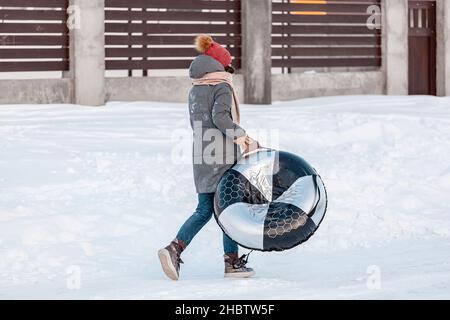 Giovane donna con snow tubing attività invernale, scivolo da neve hi Foto Stock