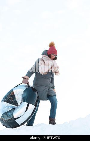 Giovane donna con snow tubing attività invernale, scivolo da neve hi Foto Stock