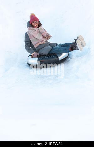 Giovane donna con snow tubing attività invernale, scivolo da neve hi Foto Stock