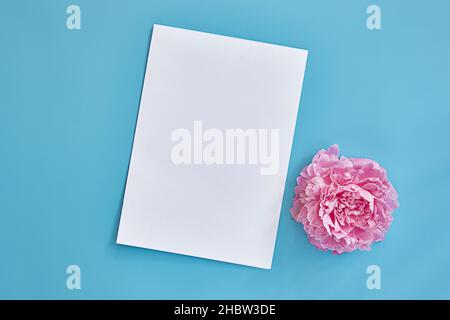 foglio di carta bianca con spazio per il testo su sfondo blu. Peony flower.Vista dall'alto, spazio di copia Foto Stock