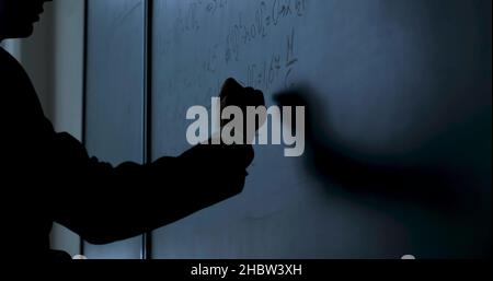 Formule di scrittura dello scienziato sulla lavagna. Mano con gesso ha scritto formule di fisica su lavagna nera close up 4K Foto Stock