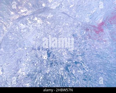 Lo sfondo astratto del taglio di ghiaccio è blu con una tinta viola e un punto sfocato cremisi. Foto Stock