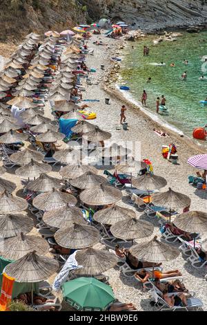 Saranda, Albania - 29 luglio 2021: La gente visita la spiaggia del monastero costiero. Saranda si trova su un golfo di mare aperto del Mar Ionio all'interno del Mediterrano Foto Stock