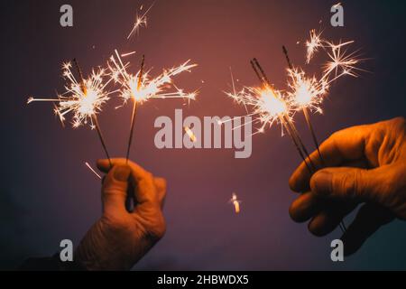 Le mani della coppia di anziani azienda brilla per celebrare il nuovo anno Foto Stock