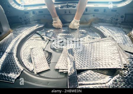 Il personale addetto all'assistenza auto installa materiale insonorizzante all'interno dell'abitacolo, isolamento acustico. Foto Stock