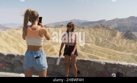 Amabile ragazze caucasiche che esprimono emozioni positive alla macchina fotografica. Foto all'aperto di raffinate sorelle che si posano sullo sfondo con montagne nel Mojav Foto Stock