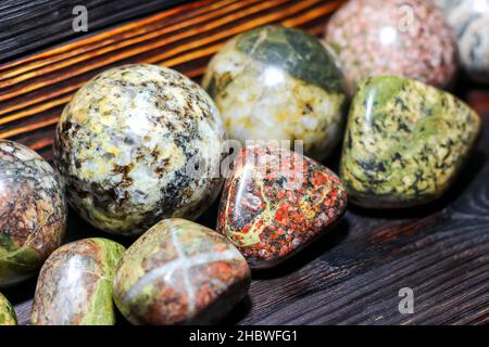 Collezione di pietre lavorate di diversi colori - magmatite - su sfondo ligneo Foto Stock