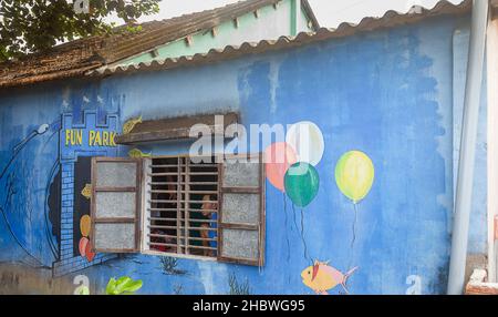 Una casa a Tam Ky con murales dipinti e persone nella finestra. Foto Stock