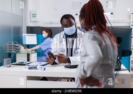 Medico che dà una bottiglia di pillole a donna incinta con malattia in ufficio medico. Paziente in attesa di bambino che riceve un pallone con medicinale da prescrizione medica per il trattamento della malattia Foto Stock