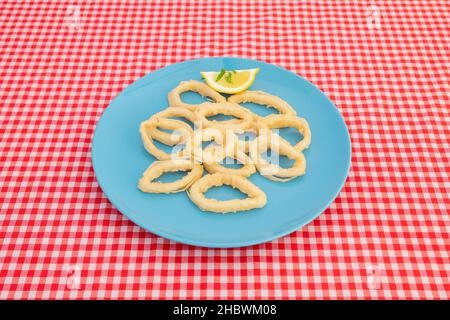 Tipica tapa spagnola di anelli di calamari martoriati con farina di grano e uova fritte in olio d'oliva su un piatto blu Foto Stock