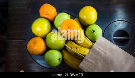 Una vista dall'alto di un sacchetto di carta con frutta acquistata dal mercato sul piatto di ferro della stufa a legna Foto Stock