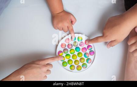 Bambini che giocano con il giocattolo push pop fidget sul pavimento Foto Stock