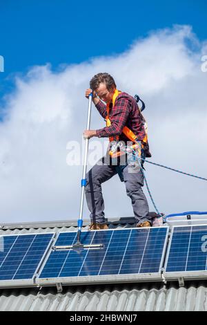 Commercianti pulizia pannelli solari sul tetto della casa Foto Stock