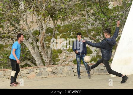 Giovani uomini marocchini che giocano a calcio fuori dalla medina di Chefchaouen, Marocco. Foto Stock