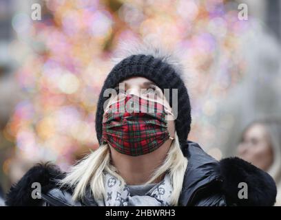 New York, Stati Uniti. 21st Dic 2021. Una donna indossa una maschera in tessuto tartan mentre guarda le decorazioni natalizie di Saks Fifth Avenue vicino al Rockefeller Center Christmas Tree a New York City martedì 21 dicembre 2021. New York continua a creare record per i casi COVID positivi man mano che i viaggi di vacanza si sollevano. Foto di John Angelillo/UPI Credit: UPI/Alamy Live News Foto Stock