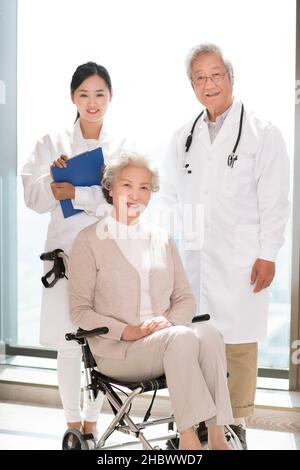 Medico e una donna anziana in sedia a rotelle Foto Stock