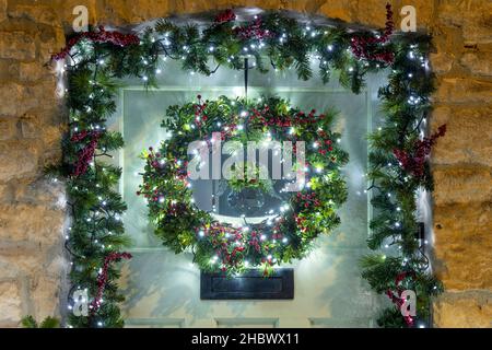 Corona di Natale e angeli ali sulla porta anteriore di un cottage in pietra. Stow on the Wold, Cotswolds, Gloucestershire, Inghilterra Foto Stock