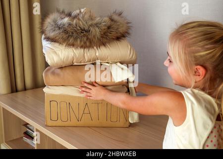 Confezione da donazione con abiti invernali sul tavolo. Foto Stock